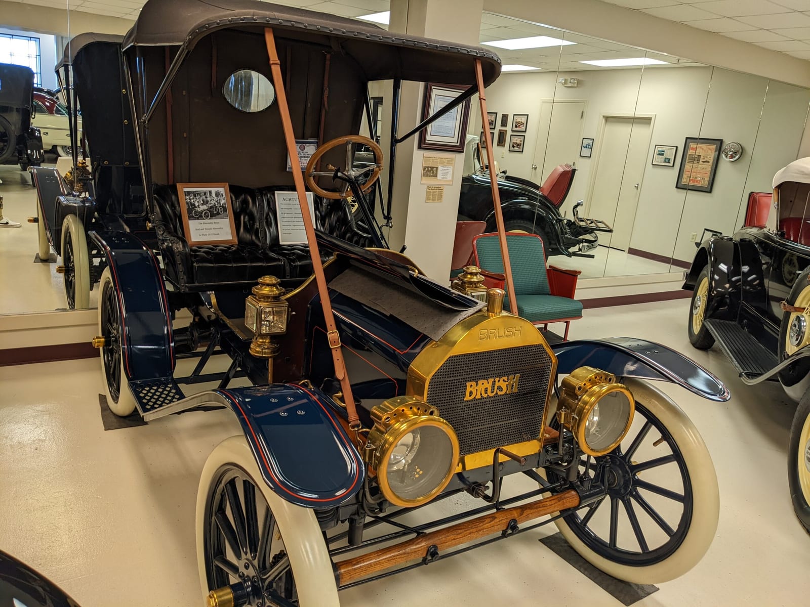 The 1910 Brush Roadster at the Swope Museum, brass lamps and white tires, with the collection behind it
